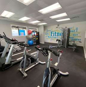 A gym with a row of stationary bikes and a wall with fitness related words. at Sycamore Square  Apartments, Arizona, 85202