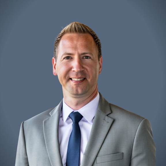 A man in a grey suit and blue tie.