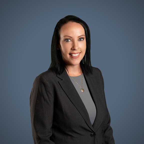 a woman with black hair and a gray shirt is standing in front of a blue background