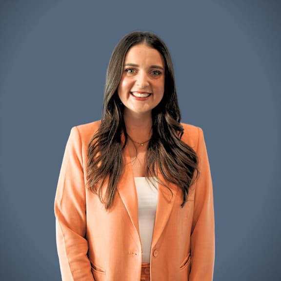 A woman with long dark hair wearing an orange blazer and white top.