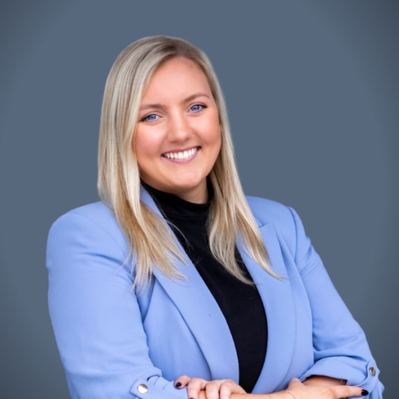 a smiling woman in a blue jacket with her arms crossed