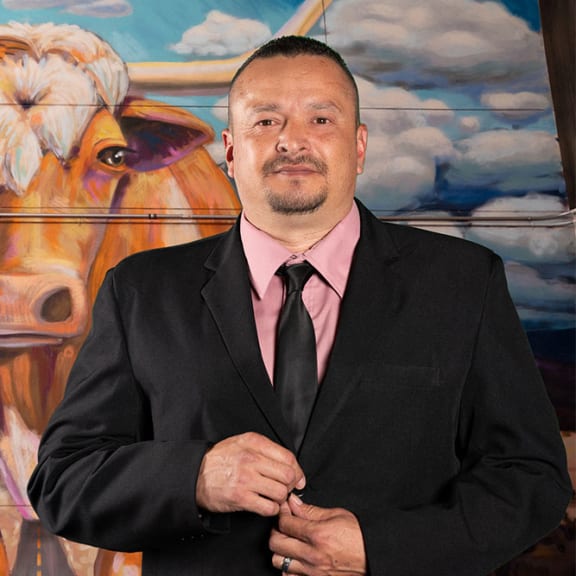 a man in a suit and tie standing in front of a painting of a cow
