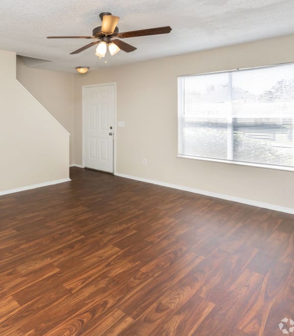 an empty living room with wood flooring and a ceiling fan