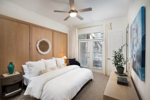 a bedroom with a large white bed and a large painting on the wall