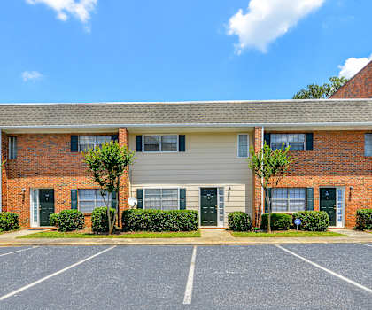 a red brick house with a parking lot in front of it
