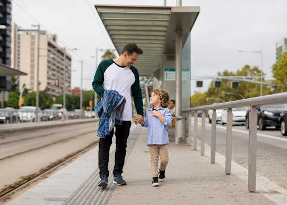A man and a child are walking together on a sidewalk.