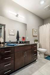 Bathroom with dark cabinets and light tile floors at The Villas at Mahoney Park