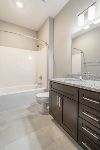 Bathroom with granite counter tops and a bathtub at 360 at Jordan West