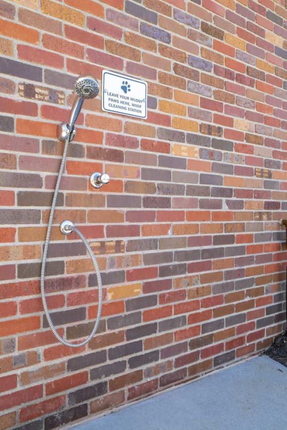 a pet wash shower head on the side of a brick wall