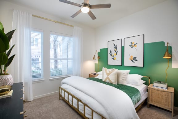 a bedroom with a green accent wall and a ceiling fan