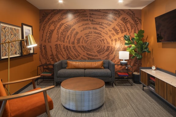 a room with a couch and chair in front of a wall with a design on it