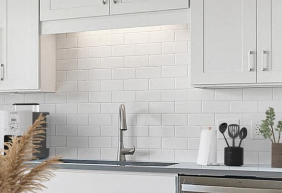 a white kitchen with white subway tiles and a sink