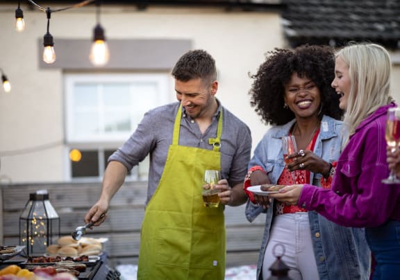 a group of people standing around a grill cooking food