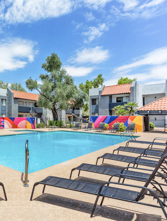 A pool surrounded by lounge chairs and a colorful inflatable in the background.