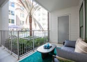 Thumbnail 8 of 19 - a patio with a couch and coffee table and a palm tree in the background