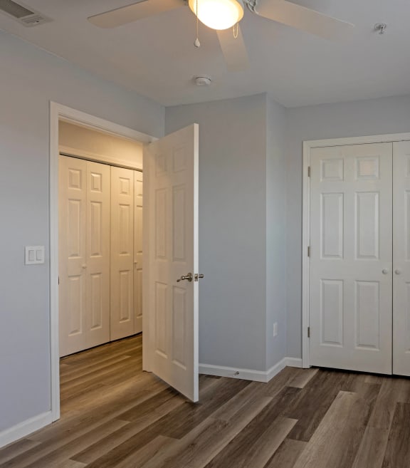 an empty room with two doors and a ceiling fan