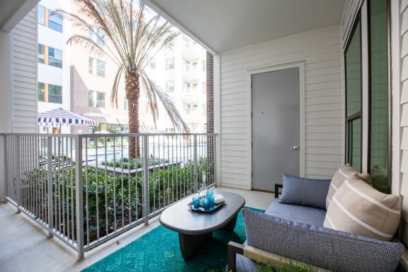 a patio with a couch and coffee table and a palm tree in the background