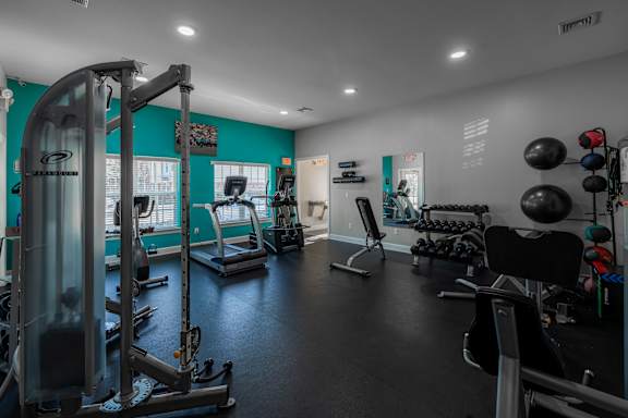 A gym with a variety of equipment including treadmills, weights, and exercise balls.