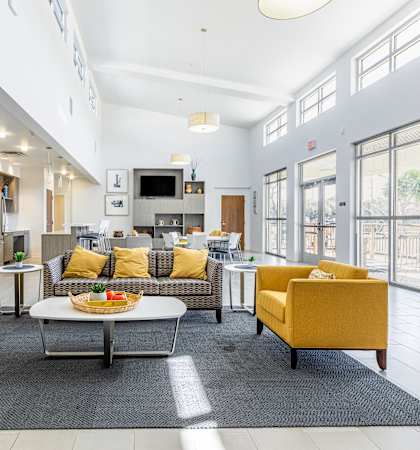 a living room with yellow couches and chairs and a table