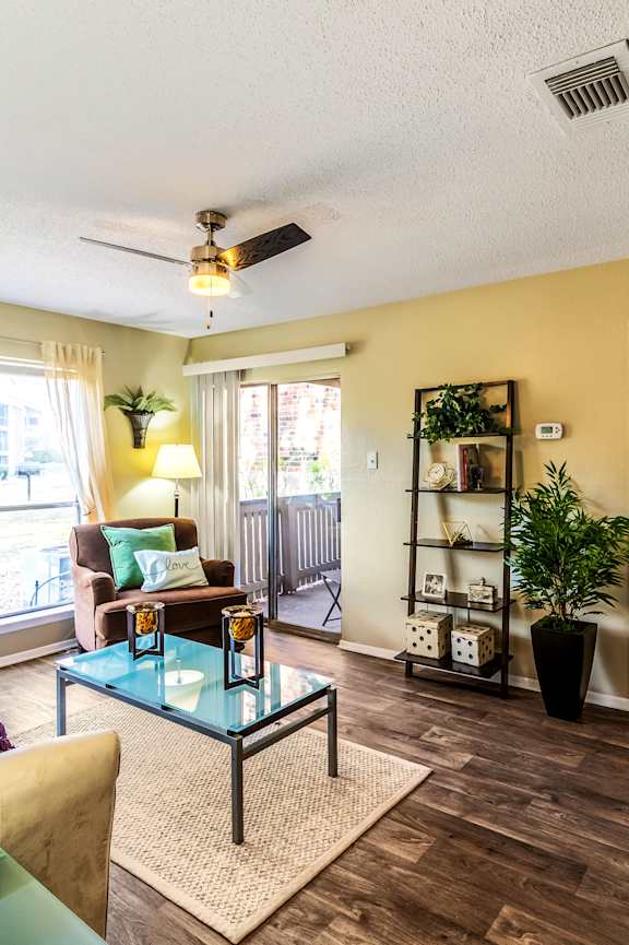 A living room with a yellow couch and a glass coffee table.
