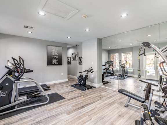 A spacious gym with a variety of equipment including treadmills, stationary bikes, and weight machines.
