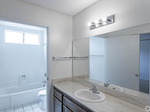 A bathroom with a white toilet, sink, and mirror.