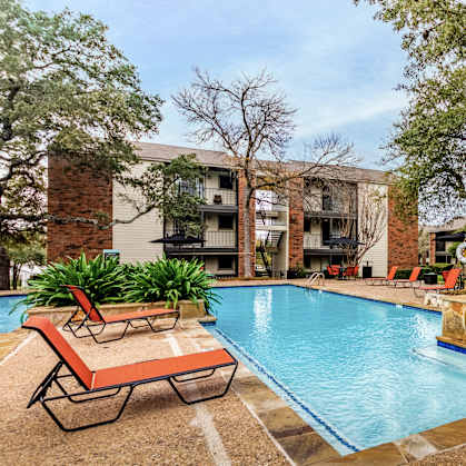 A pool with a sun lounger and a building in the background.