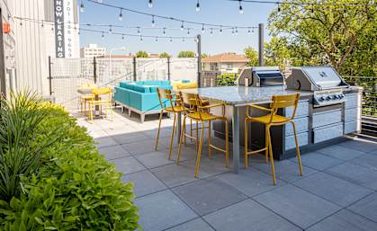 a patio with a grill and a table with yellow chairs at The Landing at 1001 NP, Fargo, North Dakota, 58102