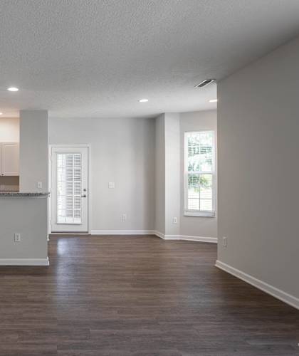 an empty living room with a kitchen with a counter top and