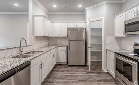 a kitchen with white cabinets and a stainless steel refrigerator