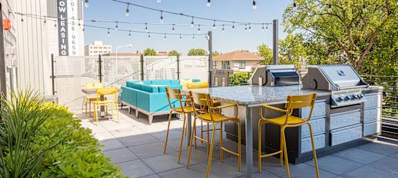 a patio with a grill and a table with yellow chairs at The Landing at 1001 NP, Fargo, North Dakota, 58102