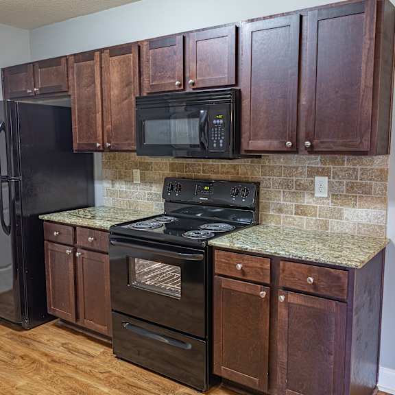 A kitchen with wooden cabinets and a black refrigerator.