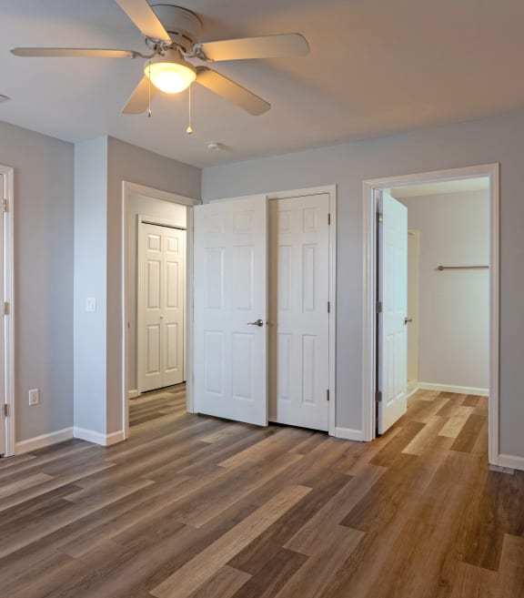 a living room with three doors and a ceiling fan