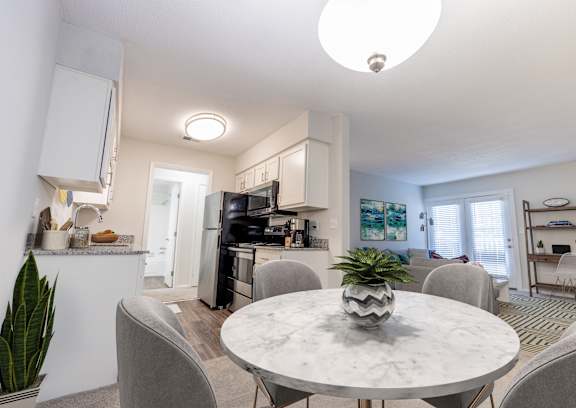 A kitchen with a table and chairs in the foreground at Gramercy Apartments, Indiana, 46032