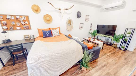A bedroom with a bed, a couch, a chair table, a TV, and a wall 605 Place Student Housing & Co-Living, St George