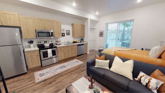 A modern kitchen with wooden cabinets and a black couch with throw pillows. 605 Place Student Housing & Co-Living, St George, 84770