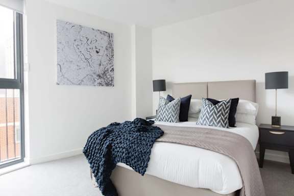 a bedroom with a bed and a large window at Vox Apartments, Manchester