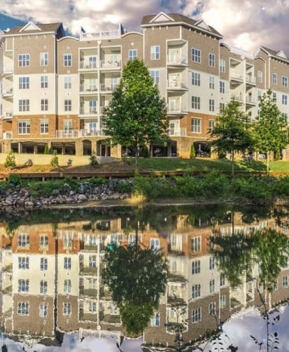 an apartment building reflected in the water of a pond