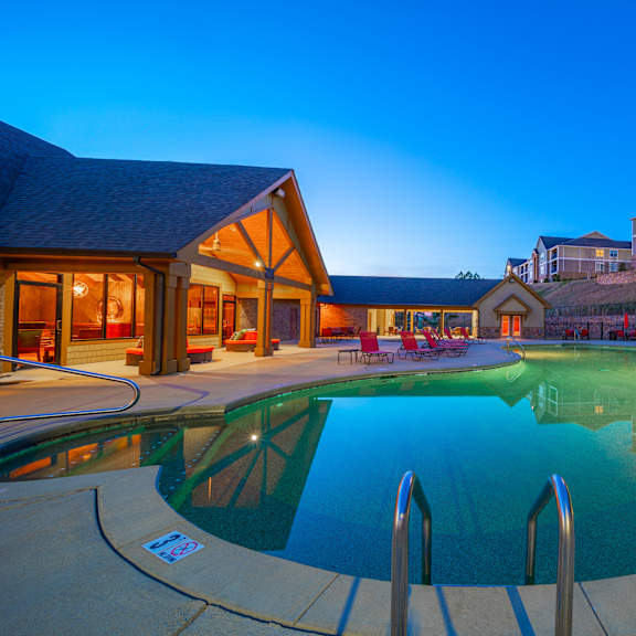 A large swimming pool in front of a building with a sunset in the background.