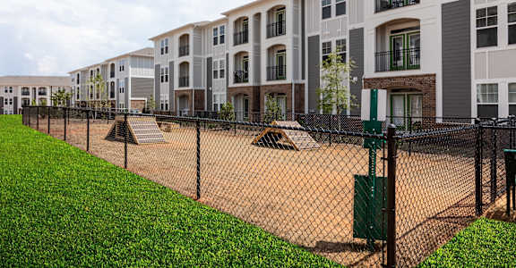 a fenced in area with apartments behind a chain link fence