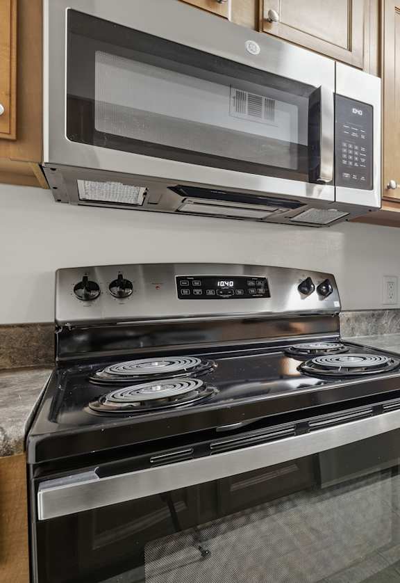 A kitchen with a black stove top oven, a microwave, and a black refrigerator.