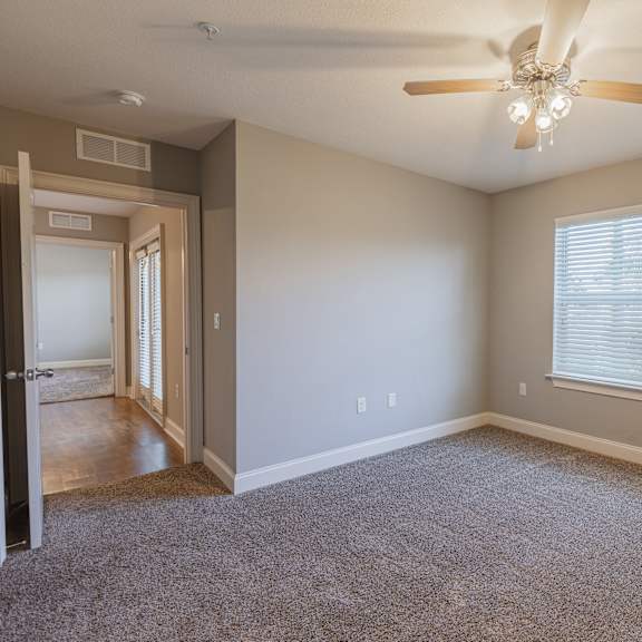 A room with a ceiling fan and a window with blinds.
