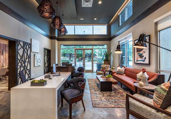 A modern living room with a white reception desk and a large window.