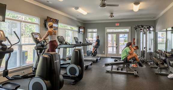 a group of people in a gym with cardio equipment