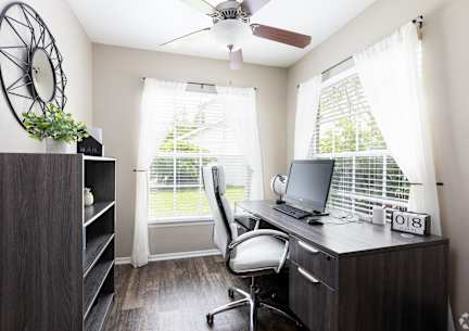 A room with a desk, chair, and a fan.