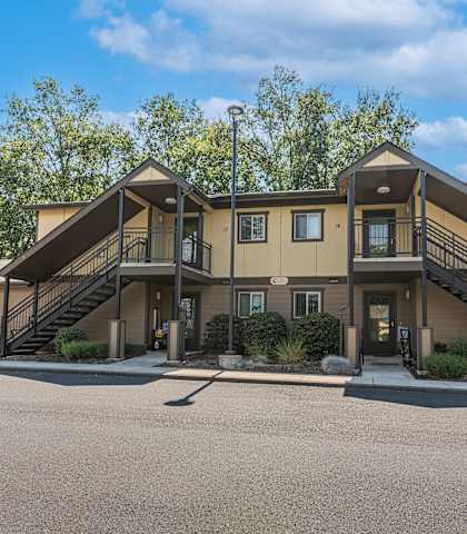 the front of a house with stairs and a parking lot