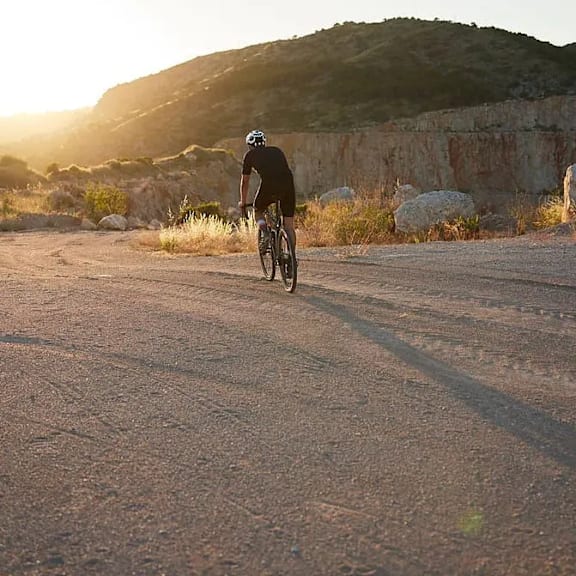 A person riding a bicycle on a dirt road.