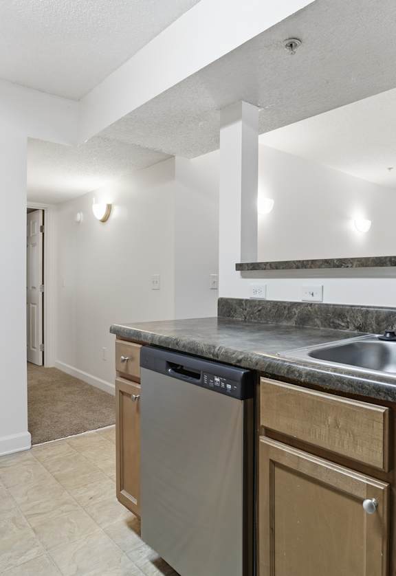 A kitchen with a white door and a black dishwasher.