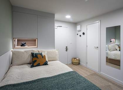 a small bedroom with a bed and a mirror