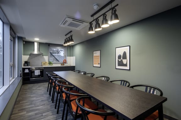 a long table and chairs in a room with a kitchen